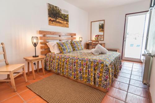 a bedroom with a bed and a chair and a window at Monte da Cabeça Gorda in Alcáçovas