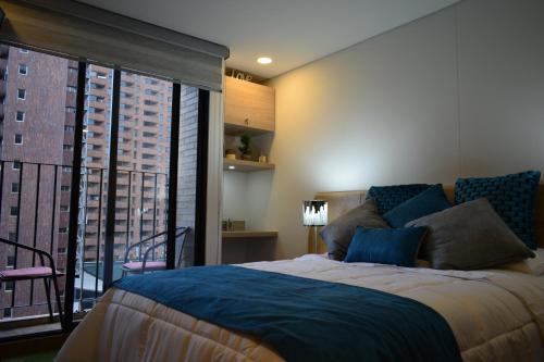 a bedroom with a large bed and a large window at TOSCANO S Aparta Estudio Hospedaje Amoblado Torre 2 Equilibrium in Bogotá