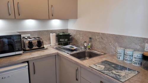 a kitchen counter with a sink and a microwave at Vitaver j in Burray Village