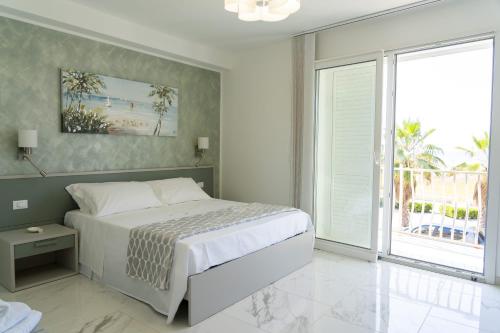 Un dormitorio blanco con una cama y una ventana grande. en Il riflesso, en Pozzallo