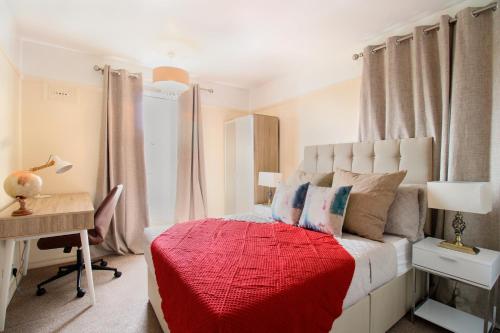 a bedroom with a bed with a red blanket and a desk at Virexxa Aylesbury Centre - Executive Suite - 2Bed Flat with Free Parking in Aylesbury