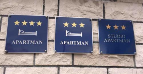 two blue signs with gold stars on a brick wall at Apartments Bruno in Split