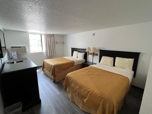 a hotel room with two beds and a desk at Dickinson Inn in Dickinson