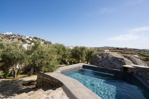 a swimming pool in a villa with rocks and trees at Ikies of Mykonos in Mýkonos City