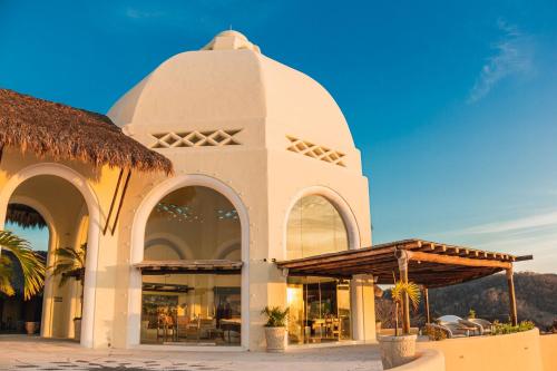 a large white building with a thatch roof at Quinta Real Huatulco in Santa Cruz Huatulco