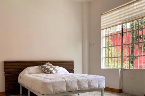 een slaapkamer met een bed en een raam bij 1C TU CASA CENTRO CDMX CONFORTABLE in Mexico-Stad