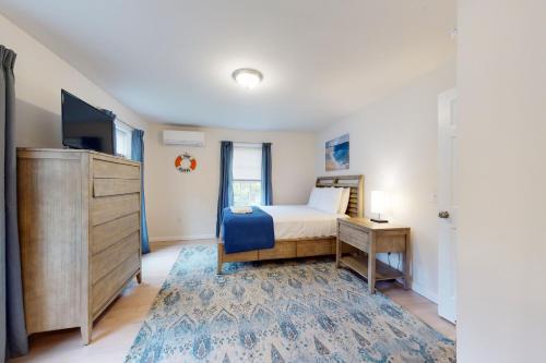 a bedroom with a bed and a dresser and a tv at Oak Bluffs Beauty in Oak Bluffs