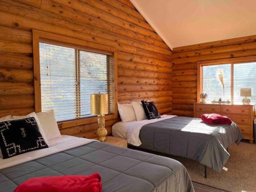two beds in a room with wooden walls and windows at Cozy Cabin Rental in Pine Mountain Club California in Frazier Park
