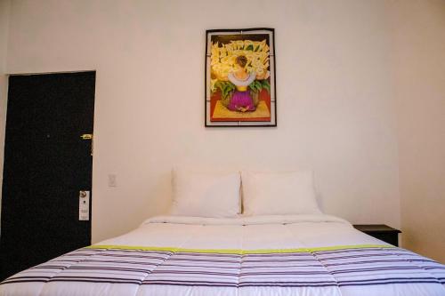 a bed in a room with a picture on the wall at Donjuan By Melida Hotel in Cabo San Lucas