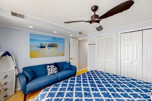 a bedroom with a blue couch and a ceiling fan at The Quarterdeck OC in Ocean City