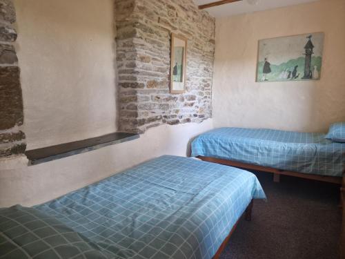 WhitlandにあるKingfisher Cottageのレンガの壁、ベッド2台が備わる客室です。