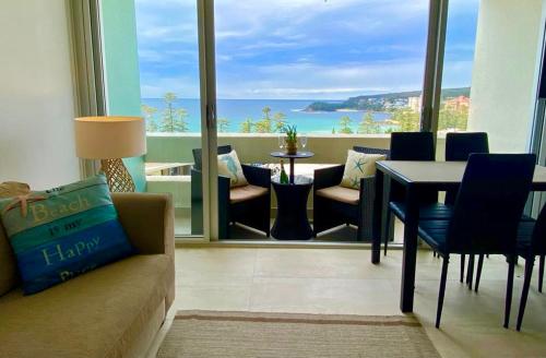 a living room with a couch and a table at Manly Ocean Beach View Sunrise & Sunset in Sydney