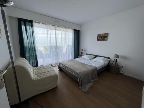 une chambre avec deux lits et une chaise et une fenêtre dans l'établissement Appartement T2 RDC avec Jardinet et Accès Direct Plage, Parking Sécurisé, Proche Commerces - FR-1-374-2, à Arcachon