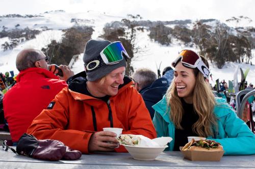a man and a woman sitting at a table eating food at Thredbo Alpine Hotel in Thredbo