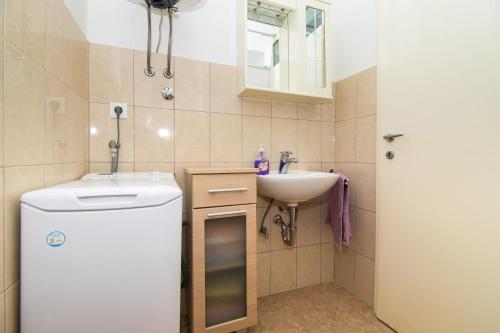 a small bathroom with a sink and a washing machine at Apartment Pave by Zamalin beach in Tribunj