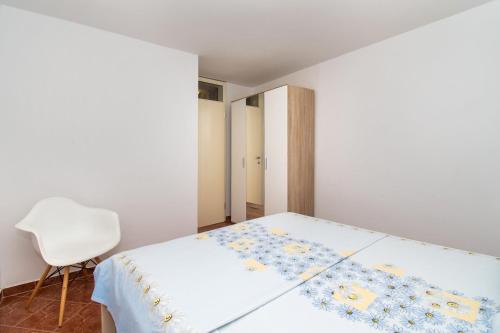 a white bedroom with a bed and a chair at Apartment Pave by Zamalin beach in Tribunj