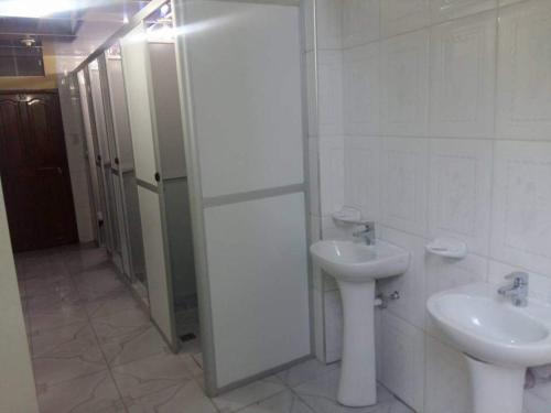 uma casa de banho branca com um lavatório e um WC em Hostal Flores em La Paz