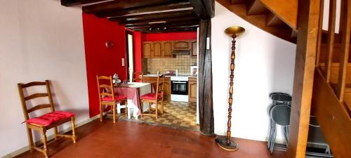 une cuisine avec des murs rouges et une table et des chaises dans l'établissement Maison accueillante à Saint-Amand-en-Puisaye avec jardin, à Saint-Amand-en-Puisaye