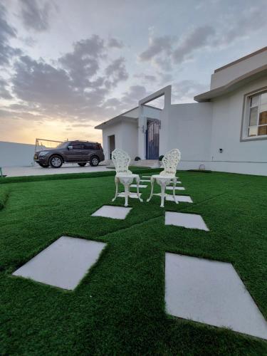 three chairs sitting on a lawn in front of a house at فيلا تل الورد in Ibri