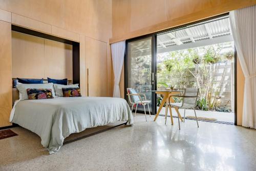 a bedroom with a large bed and a large window at Buhwi Bira Byron Bay - Studio in Byron Bay