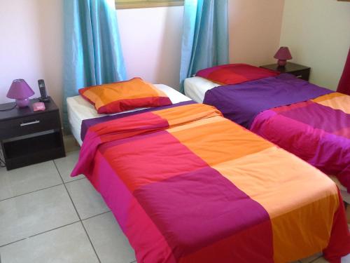 - une chambre avec 2 lits et des draps colorés dans l'établissement LE PLAISIR, au Gosier