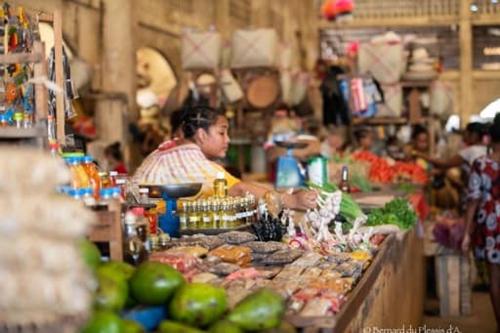 a woman standing behind a counter in a market at villa Mena in Nosy Be
