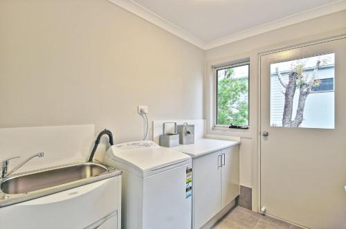 a white kitchen with a sink and a window at The Oasis of Calm by Experience Jervis Bay in Huskisson