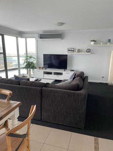 a living room with a couch and a flat screen tv at Sails Apartments in Forster