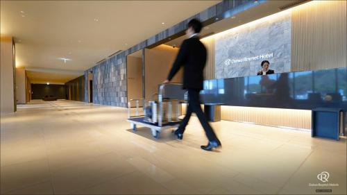 a man walking down a hallway with a luggage cart at Daiwa Roynet Hotel Kagoshima Tenmonkan PREMIER - former Daiwa Roynet Hotel Kagoshima Tenmonkan in Kagoshima