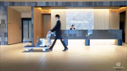 a man walking through a lobby with a luggage cart at Daiwa Roynet Hotel Kagoshima Tenmonkan PREMIER - former Daiwa Roynet Hotel Kagoshima Tenmonkan in Kagoshima