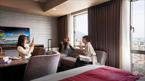 three women sitting in a hotel room with their cell phones at Daiwa Roynet Hotel Kagoshima Tenmonkan PREMIER - former Daiwa Roynet Hotel Kagoshima Tenmonkan in Kagoshima