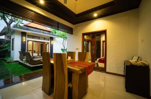 a dining room with a table and a living room at Kayu Suar Bali Luxury Villas & Spa in Sanur