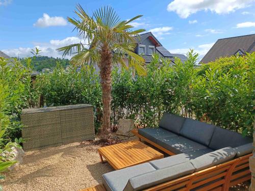 a blue couch sitting next to a palm tree at Luxus Ferienwohnung Chalet Seenähe in Schalkenmehren