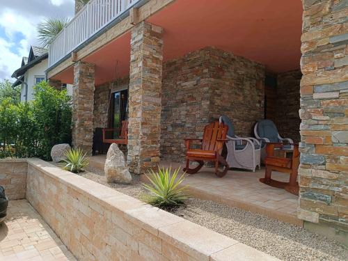 a patio with two chairs and a stone wall at Luxus Ferienwohnung Chalet Seenähe in Schalkenmehren