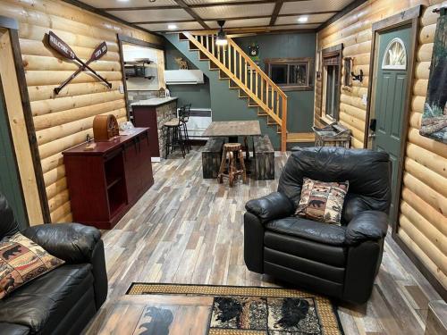 a living room with a leather couch and a table at Cubs Den - Hot Tub- Walk to Lake- Fire Pit - Kayaks in Oakland