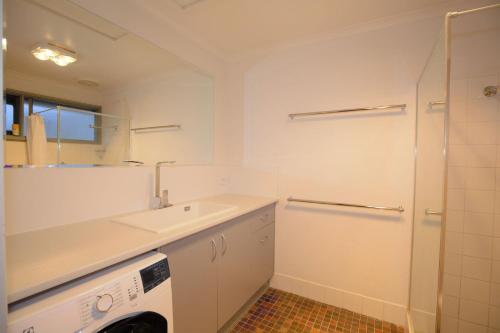 a white bathroom with a sink and a washing machine at Snowy Saga 1 46 Gippsland Street in Jindabyne