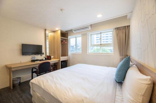 a bedroom with a bed and a desk and a television at King Hot Spring Hotel in Jiaoxi