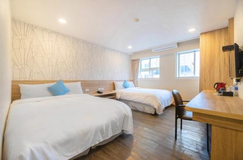 a hotel room with two beds and a desk at King Hot Spring Hotel in Jiaoxi