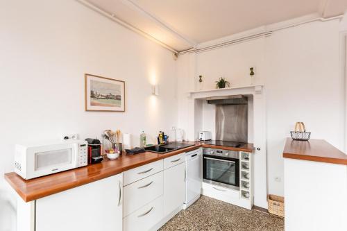 uma cozinha com armários brancos e um micro-ondas em Hypolite 1 New - Cocooning flat - 80 meters from the Port of Honfleur em Honfleur
