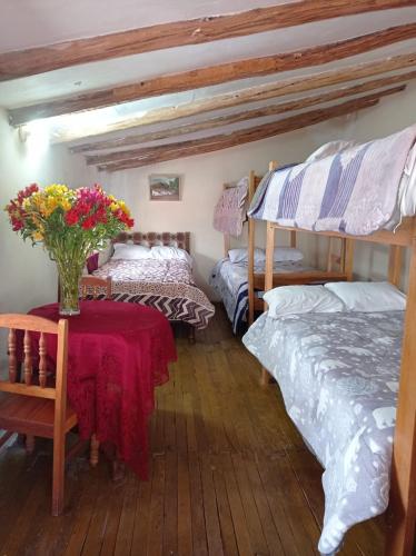 a room with two beds and a table with flowers on it at CHINA SAQRA in Cusco