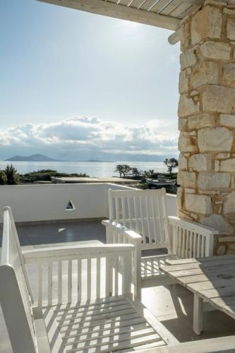 two white chairs and a table on a balcony with the ocean at Anatoli in Ambelas