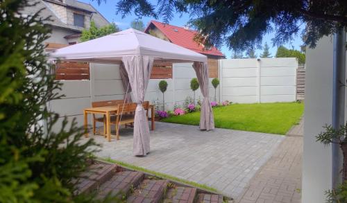 a white umbrella over a table in a backyard at Apartamenty Amarel - Wilk Morski in Stegna
