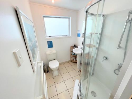 a bathroom with a shower and a toilet and a sink at Tiri Cottage - Sea Views in Oneroa by Waiheke Unlimited in Oneroa