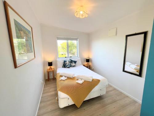 a small bedroom with a bed and two mirrors at Tiri Cottage - Sea Views in Oneroa by Waiheke Unlimited in Oneroa