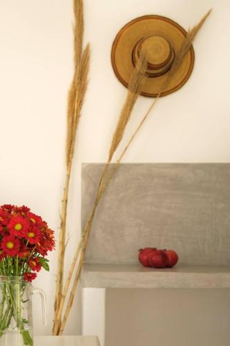 a shelf with a hat and a vase of red flowers at Anatoli in Ambelas