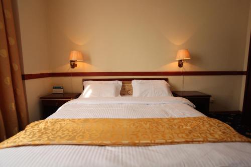 a large bed in a hotel room with two lamps at Gulistan Hotel in Dushanbe