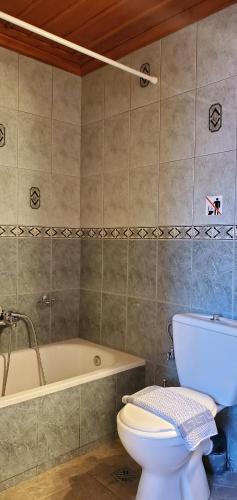 a bathroom with a toilet and a bath tub at Papigo Astraka II in Papingo