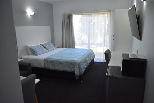 una camera d'albergo con letto e finestra di Riviana Motel a Deniliquin