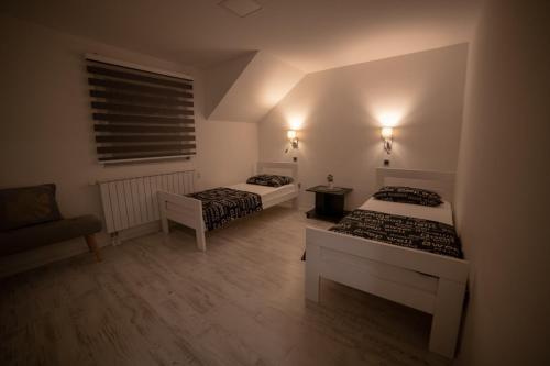 a room with two beds and a chair and a window at Konka Apartment Tuzla in Tuzla