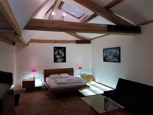 1 dormitorio con 1 cama y techo con vigas. en Grande maison familiale avec piscine couverte, en Lespignan